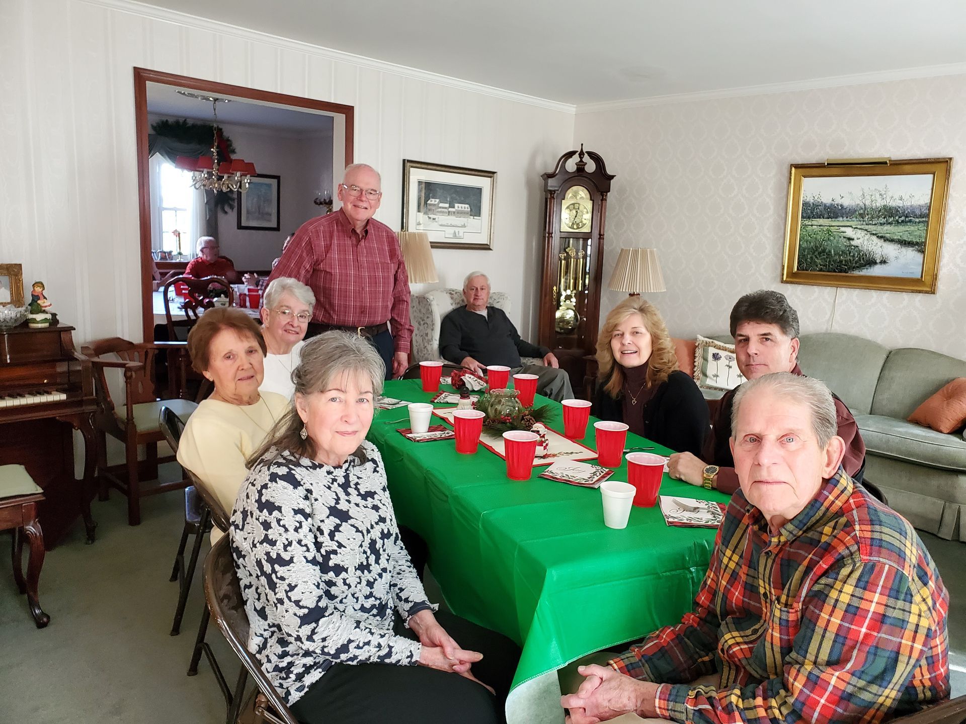 A group of people are sitting around a table with a green table cloth.