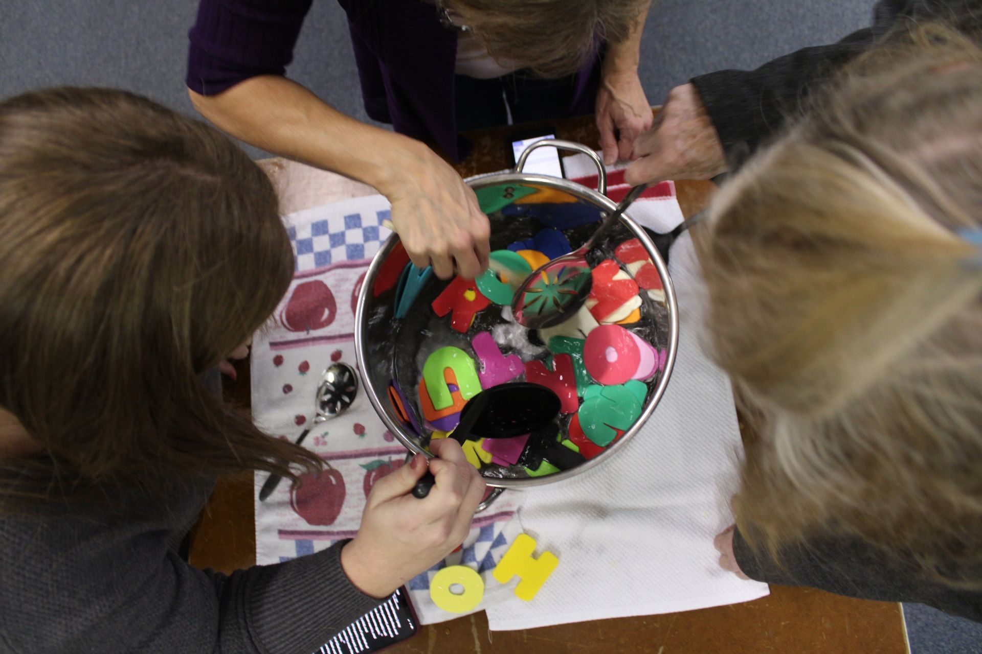 A group of people are sitting around a table making a painting