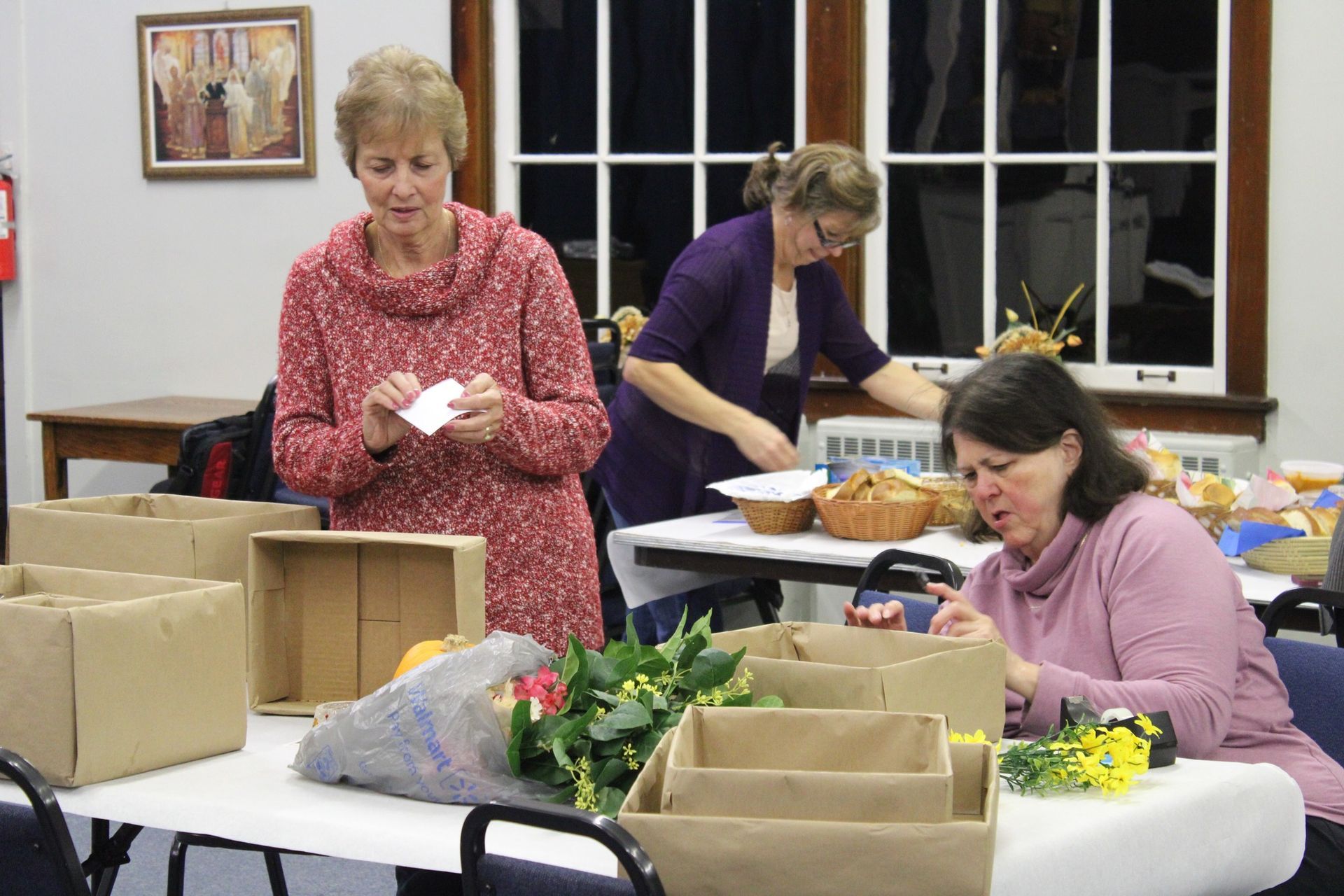 Three women are sitting at a table with boxes on it