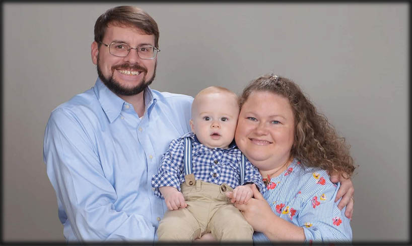A man and woman are posing for a picture with a baby.