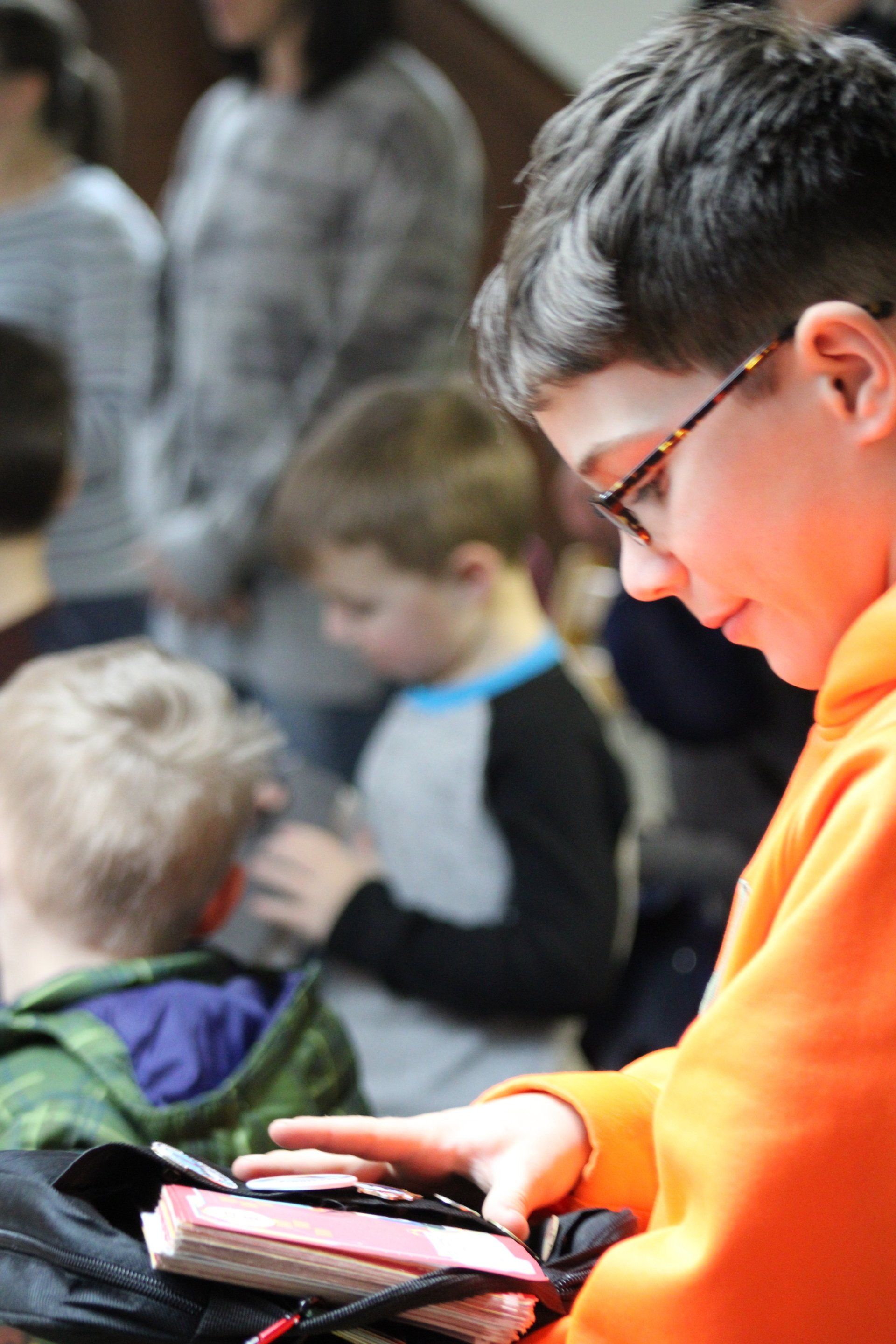 A boy in an orange hoodie is reading a book