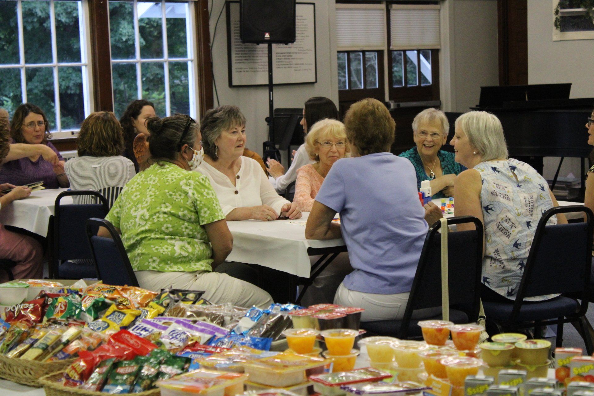 A group of women are sitting at tables talking to each other.