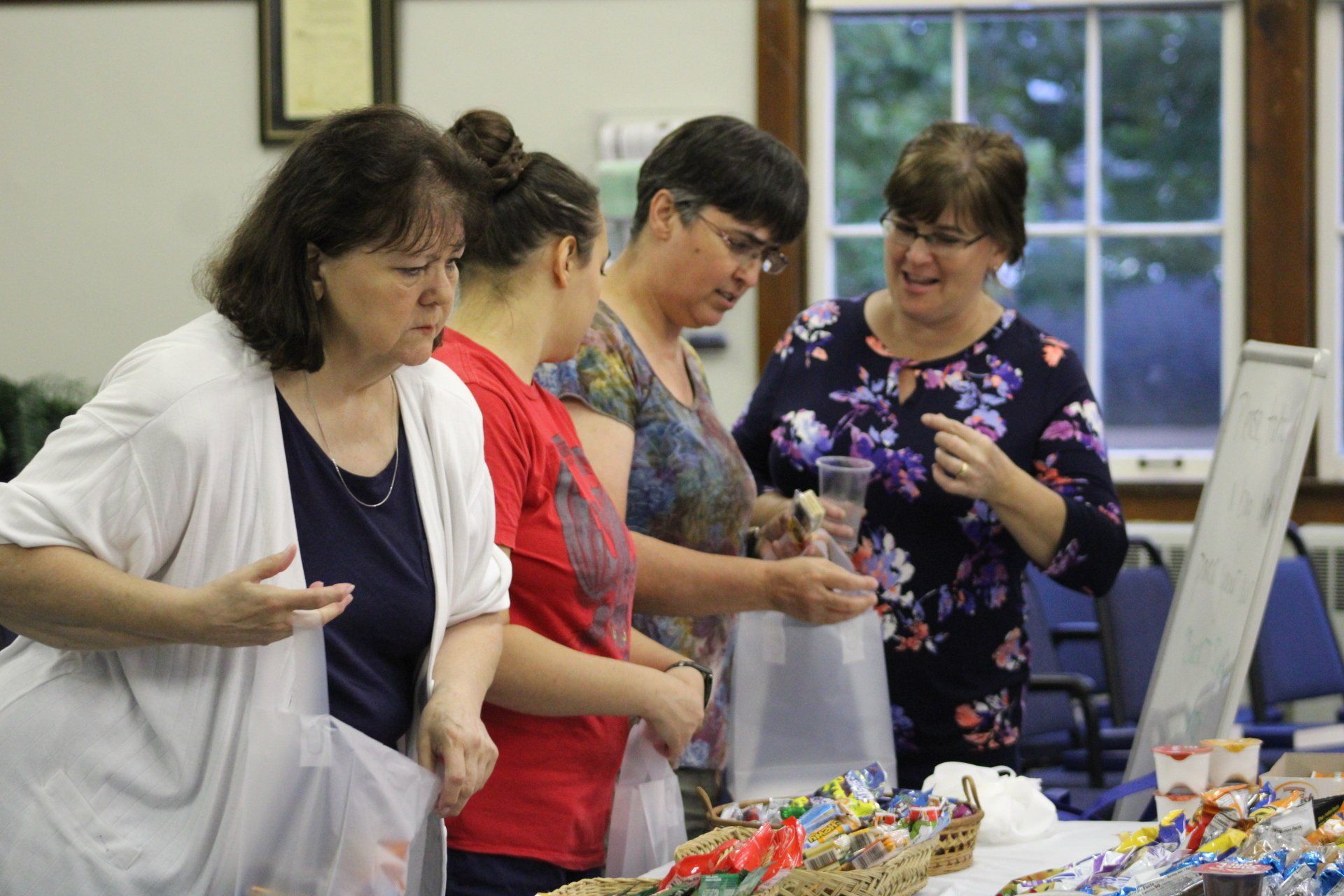 A group of women are standing around a table looking at something.