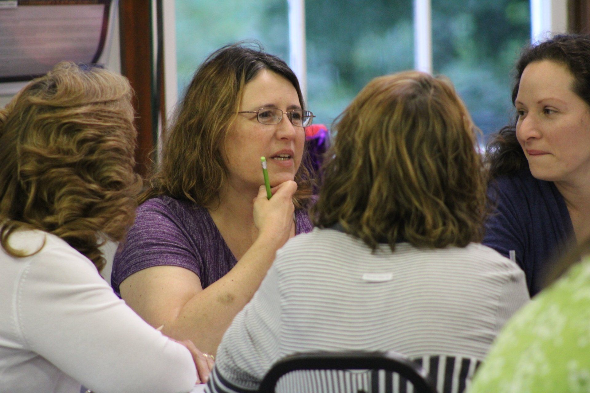 A group of women are sitting at a table talking to each other.