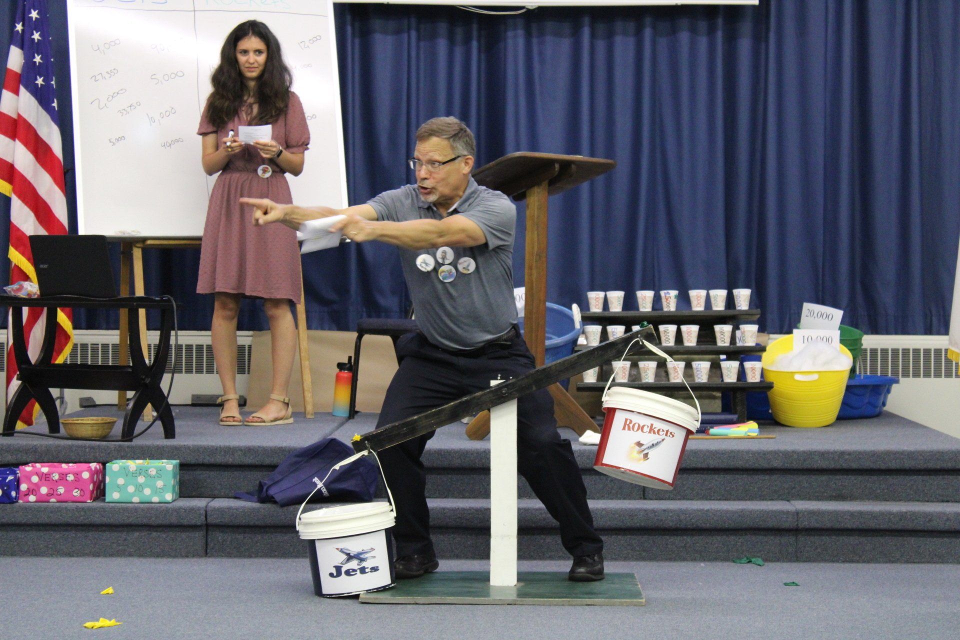 A man is standing on a scale with two buckets that say jesus on them