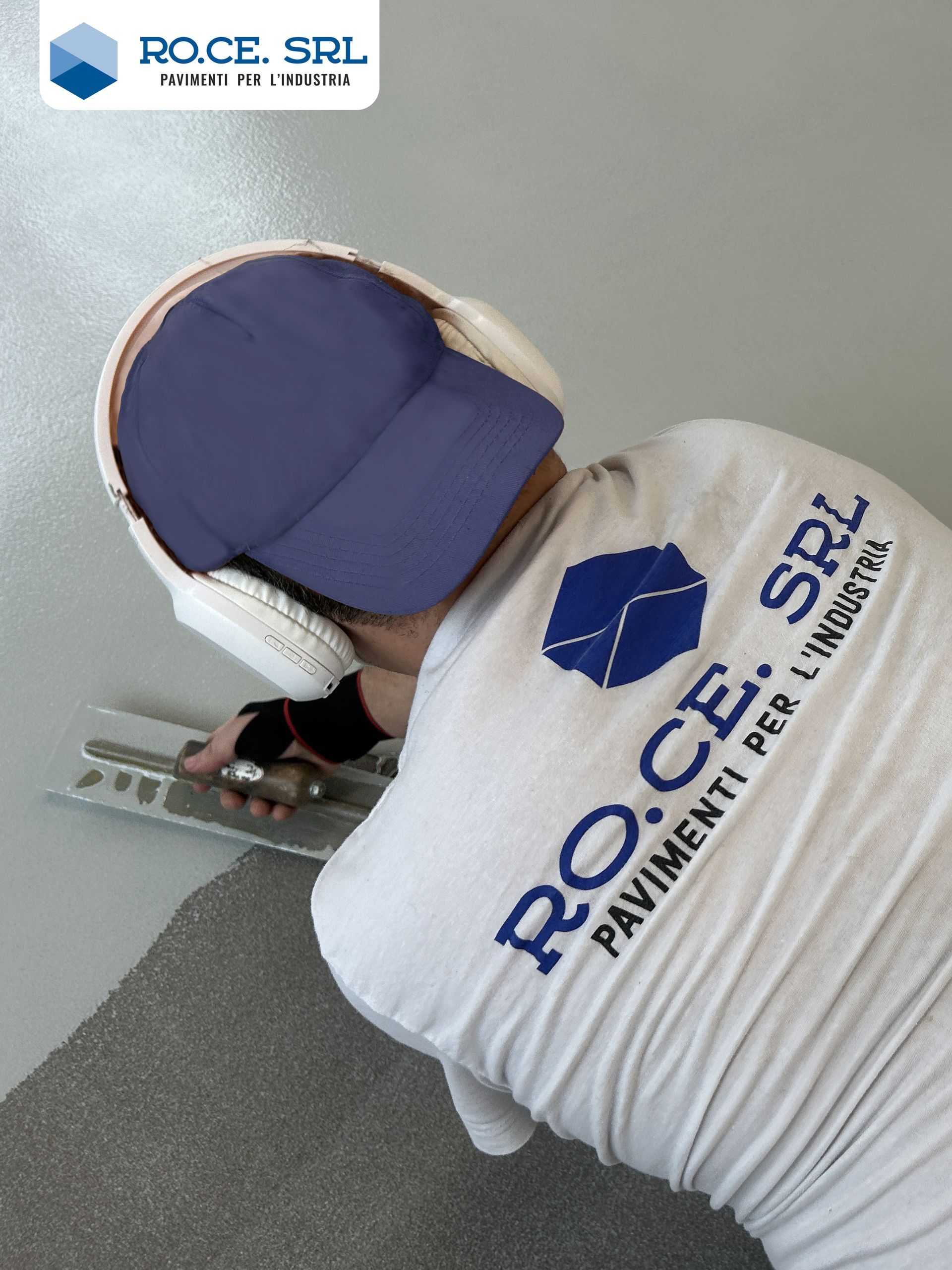 Giubbotto di sicurezza giallo con logo ROCE SRL, accanto al pavimento grigio lucido appena verniciato in un edificio.