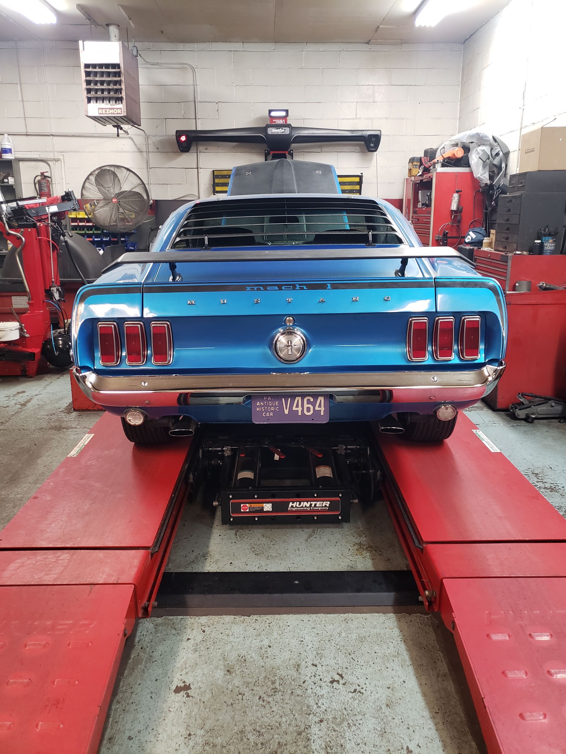 Mechanic with gloves testing car exhaust for emissions.