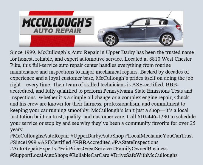 Two mechanics working on a red car in a garage, one checking the tire.