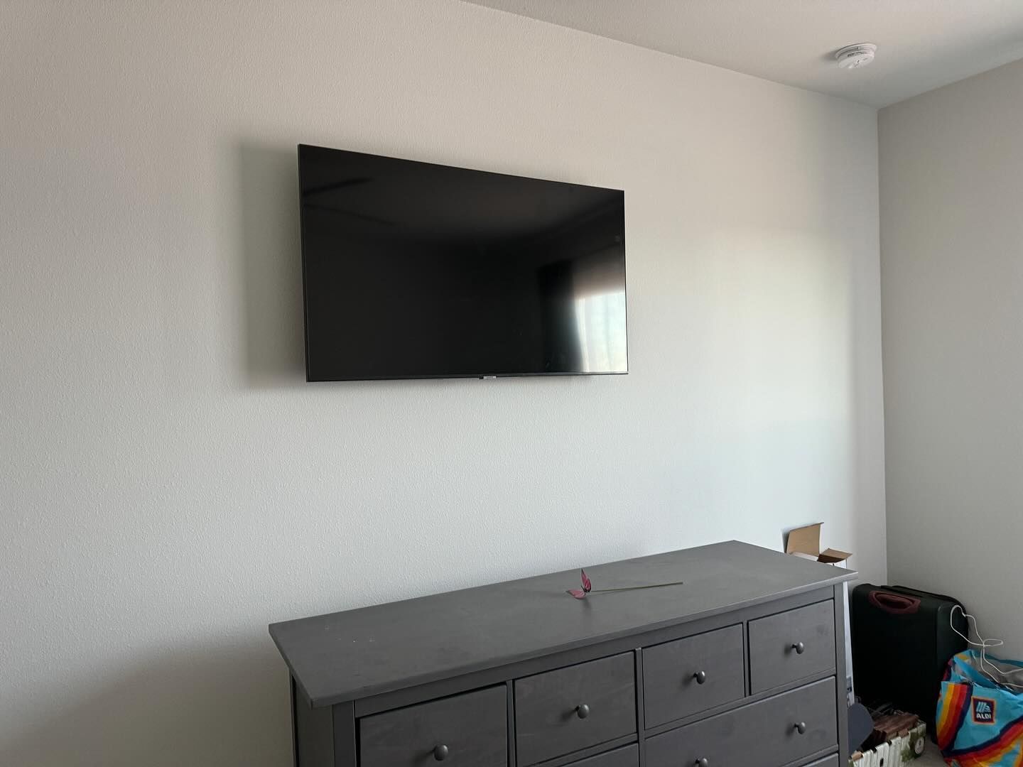 A bedroom with a dresser and a flat screen tv on the wall