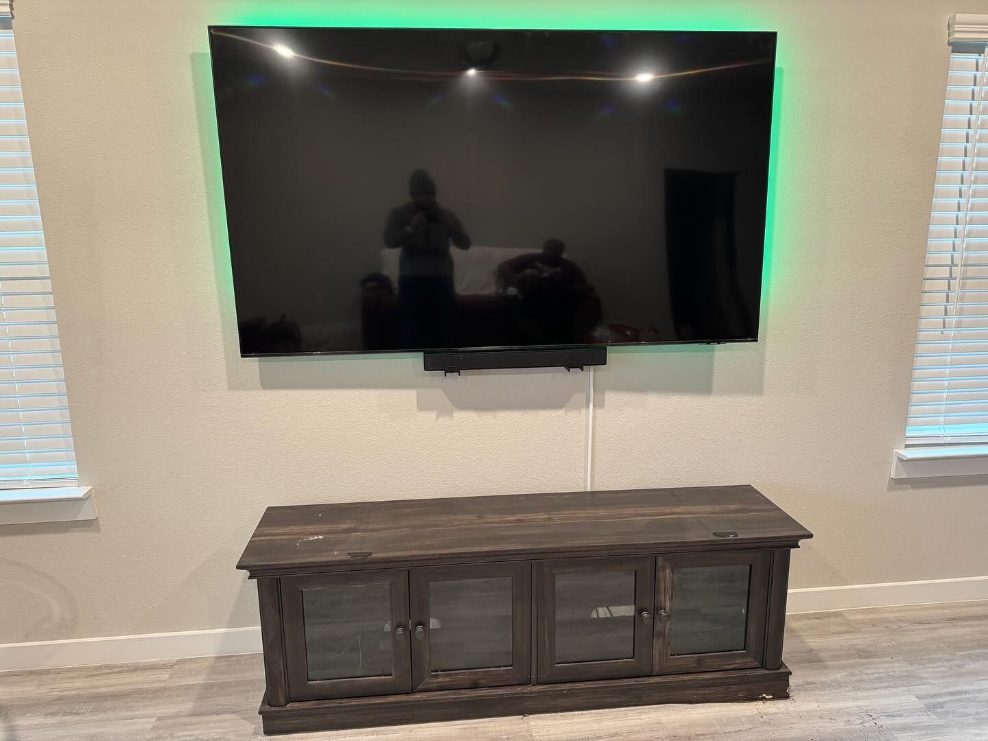 A flat screen tv is mounted on a wall above a wooden entertainment center.