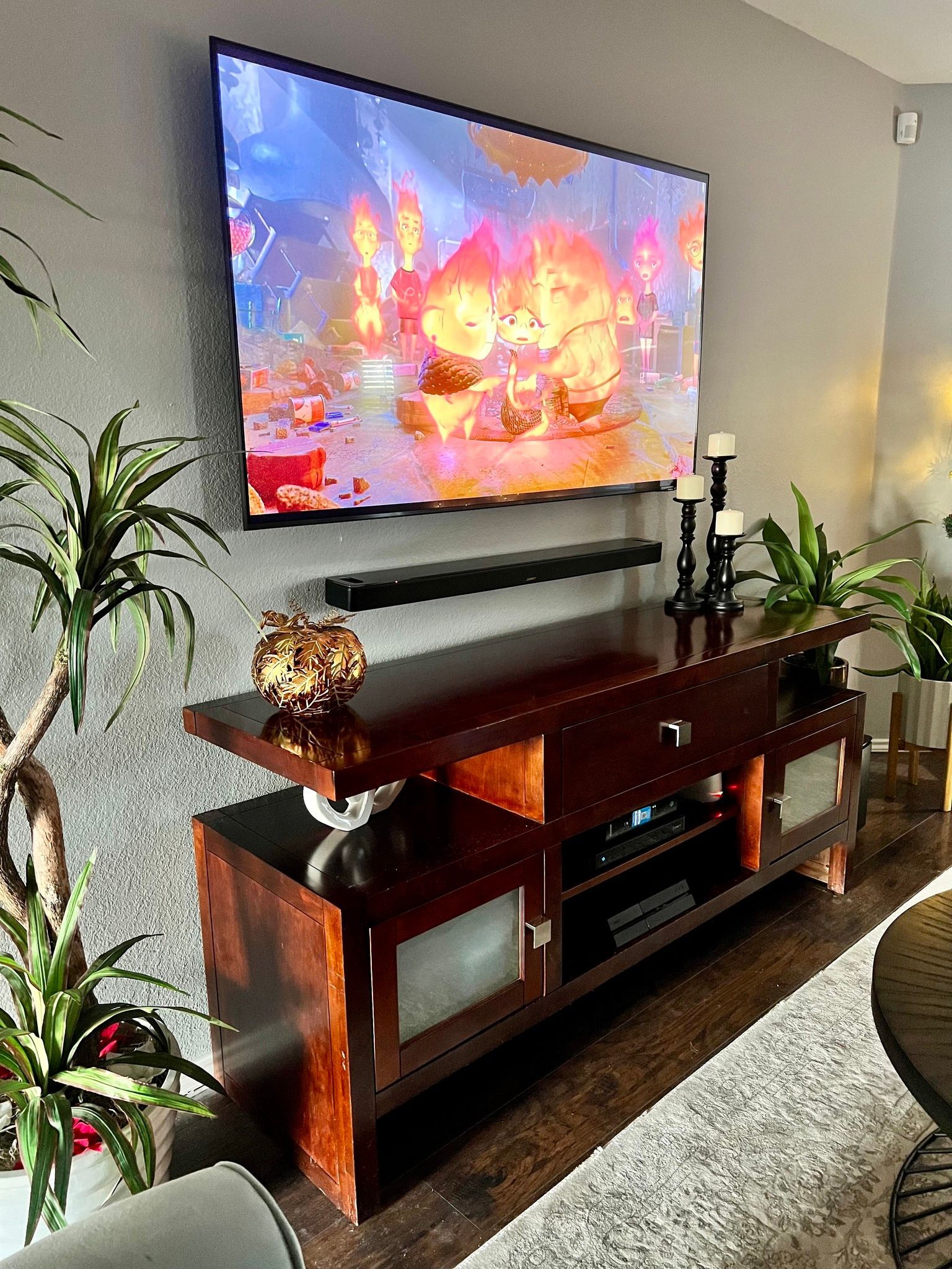A living room with a flat screen tv hanging on the wall above a wooden entertainment center.