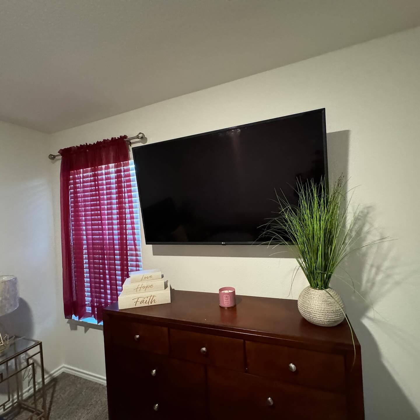A large flat screen tv is mounted on the wall above a dresser