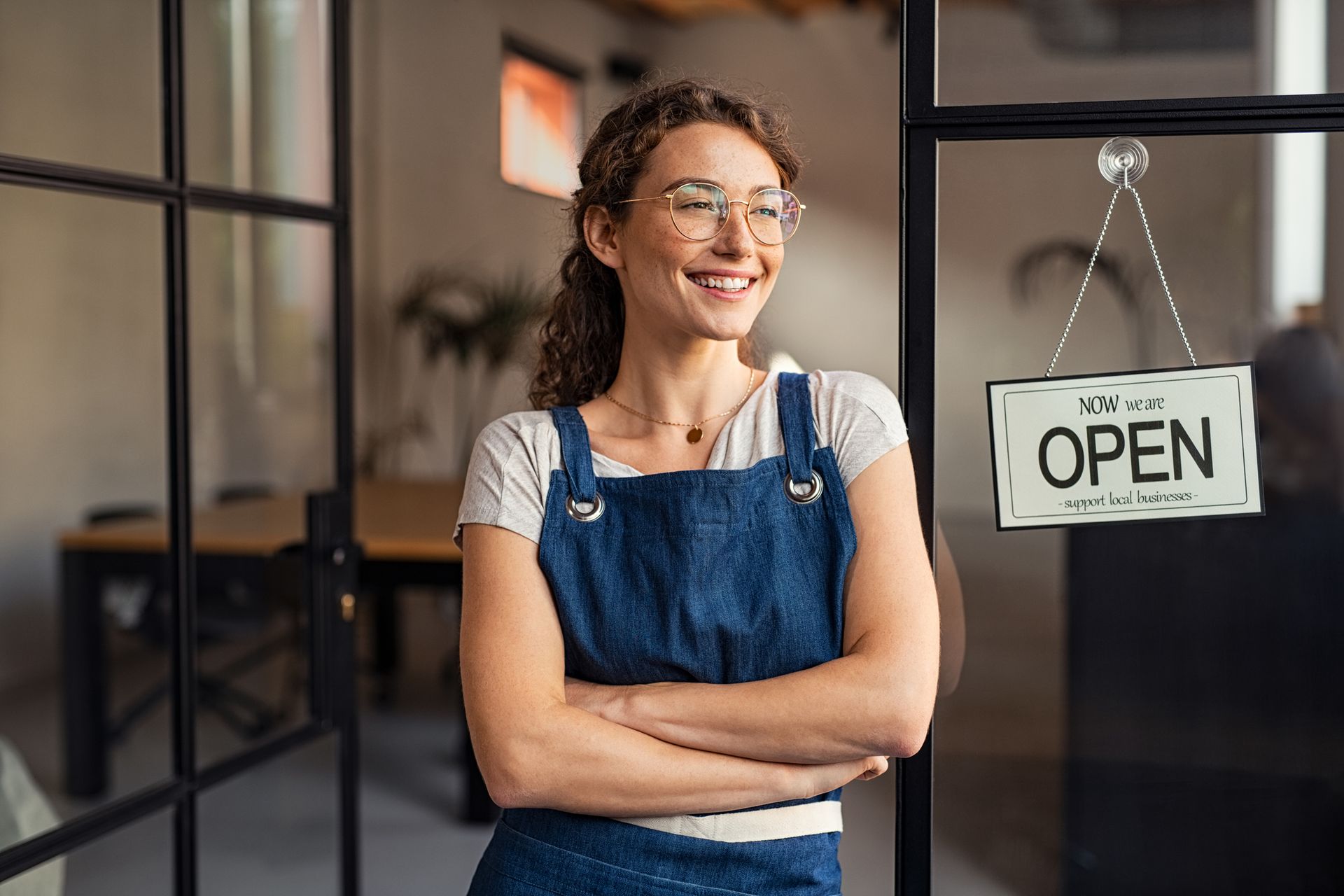 Woman in apron with arms crossed smiling by an