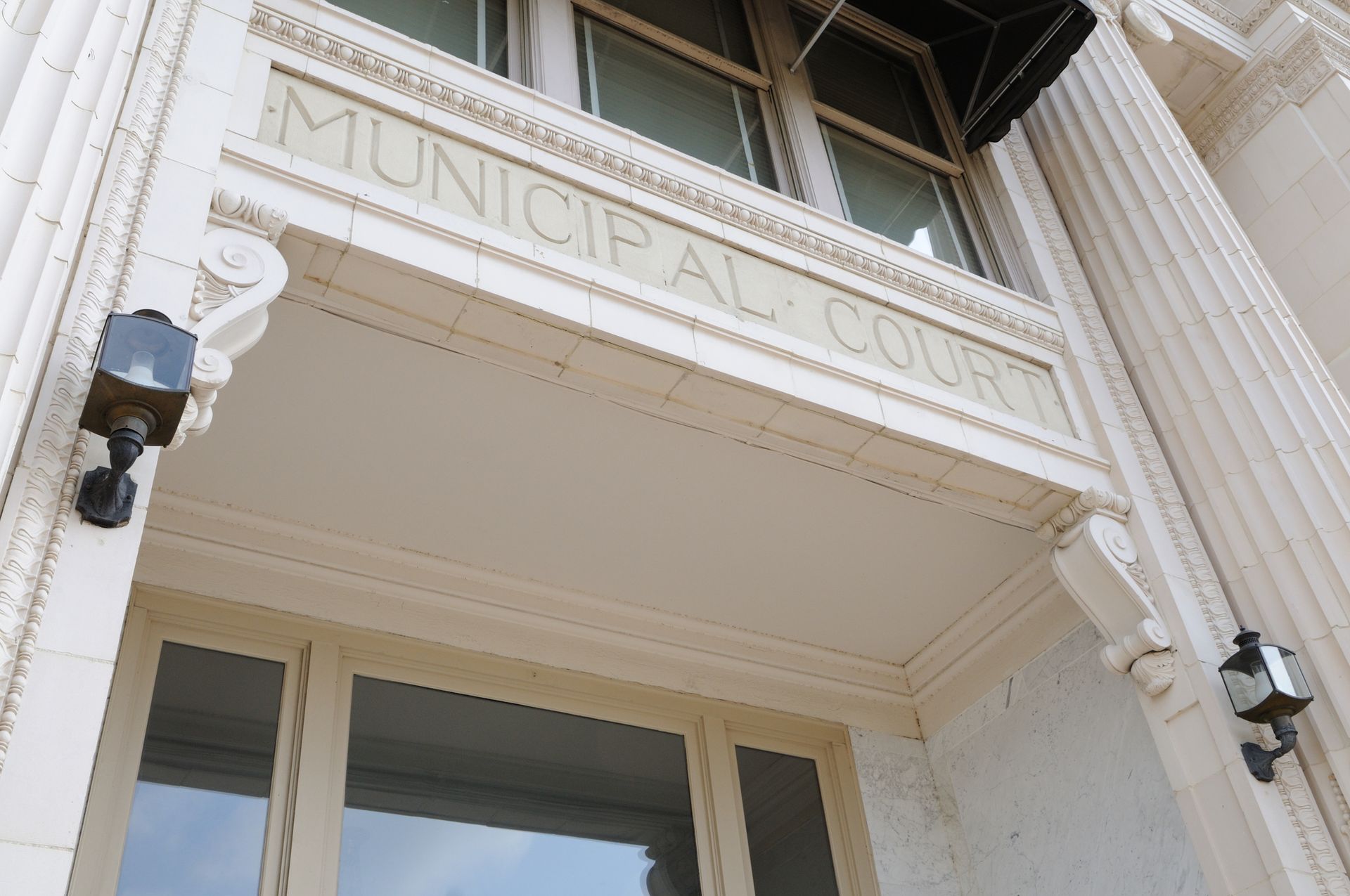 Municipal Court entrance, cream-colored building with carved lettering, flanked by sconce lights.