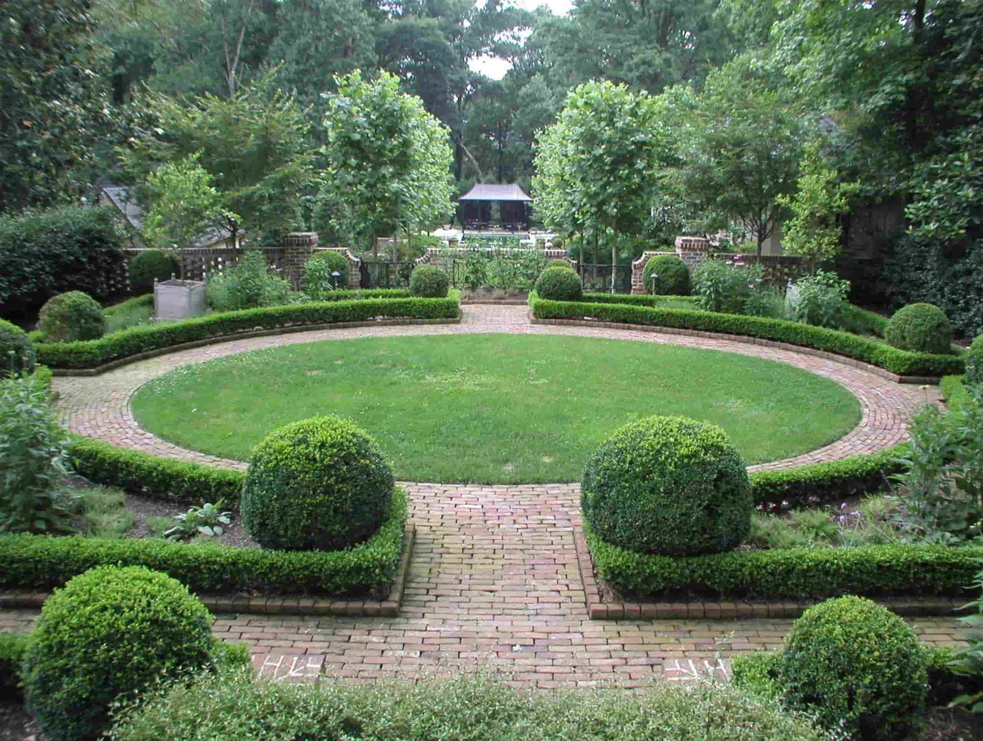 A Circular Garden with A Brick Walkway Surrounded by Bushes and Trees — D-Scapes Landscaping Services Pty Ltd in Hallidays Point, NSW