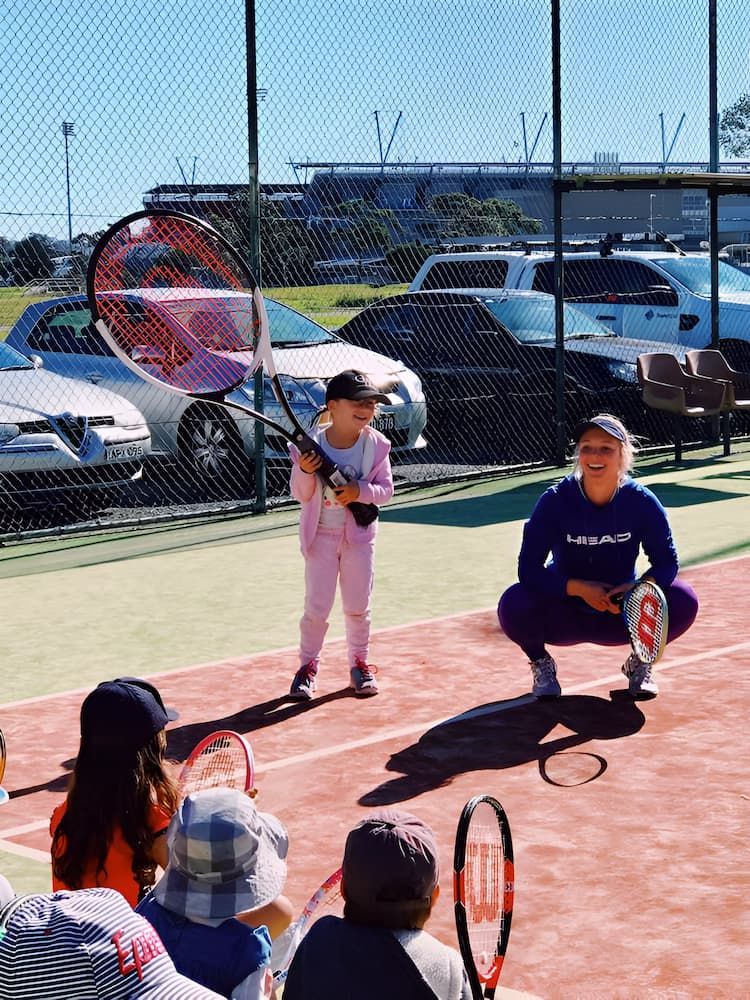 A Little Girl is Holding a Tennis Racquet on a Tennis Court — Topspin Tennis Newcastle in Lambton, NSW