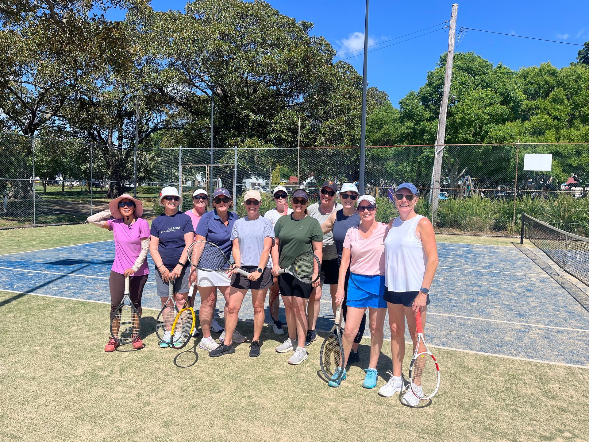 Group of People Posing With Tennis Rackets on a Court Under a Sunny Sky — Topspin Tennis Newcastle in Lambton, NSW