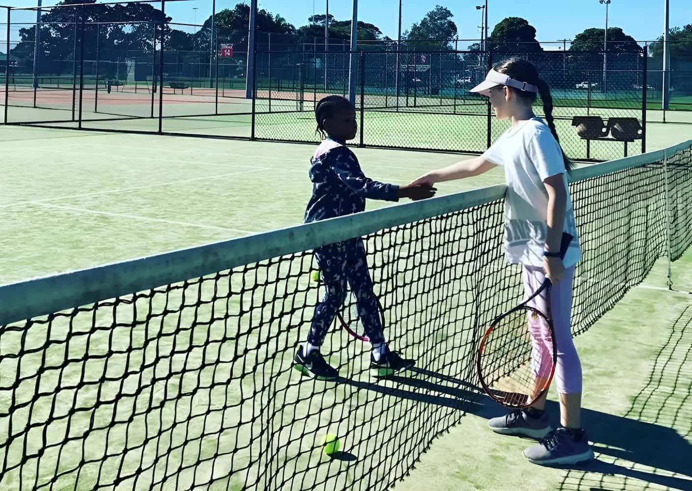 Two Young Girls Are Shaking Hands on a Tennis Court — Topspin Tennis Newcastle in Lambton, NSW