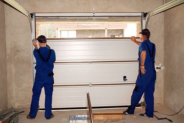 Two men are installing a garage door in a garage.