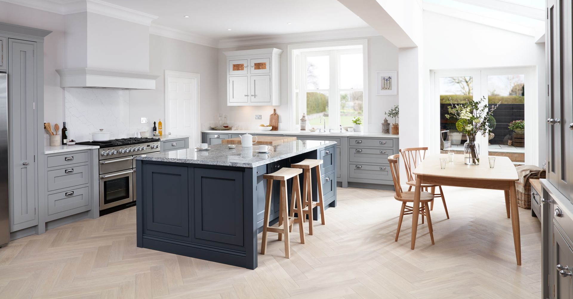 Modern open-plan kitchen and dining area with cream cabinetry, a central island, and a circular wooden dining table.