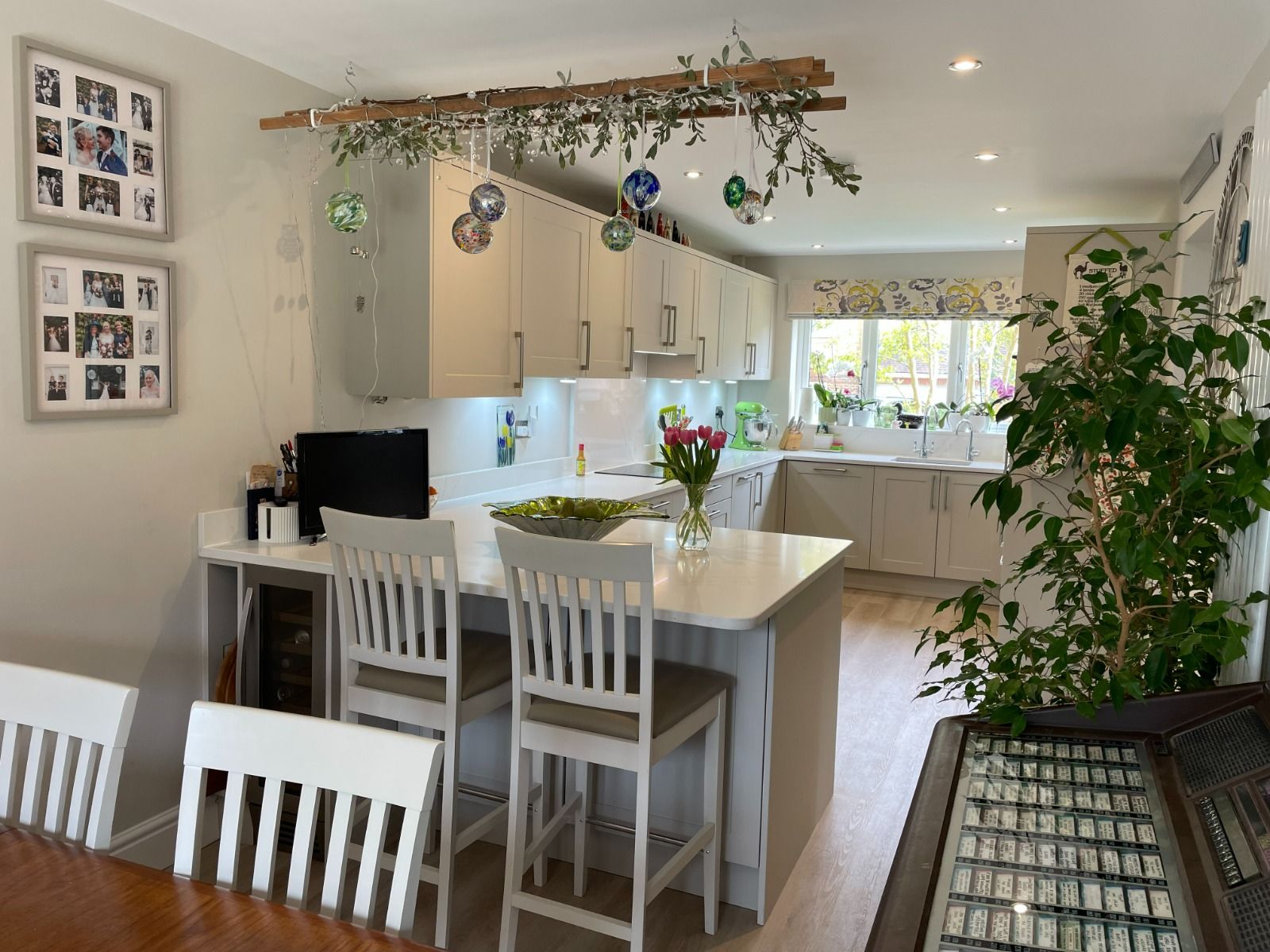 Bright, modern kitchen and dining area with white chairs, island, and large window overlooking greenery