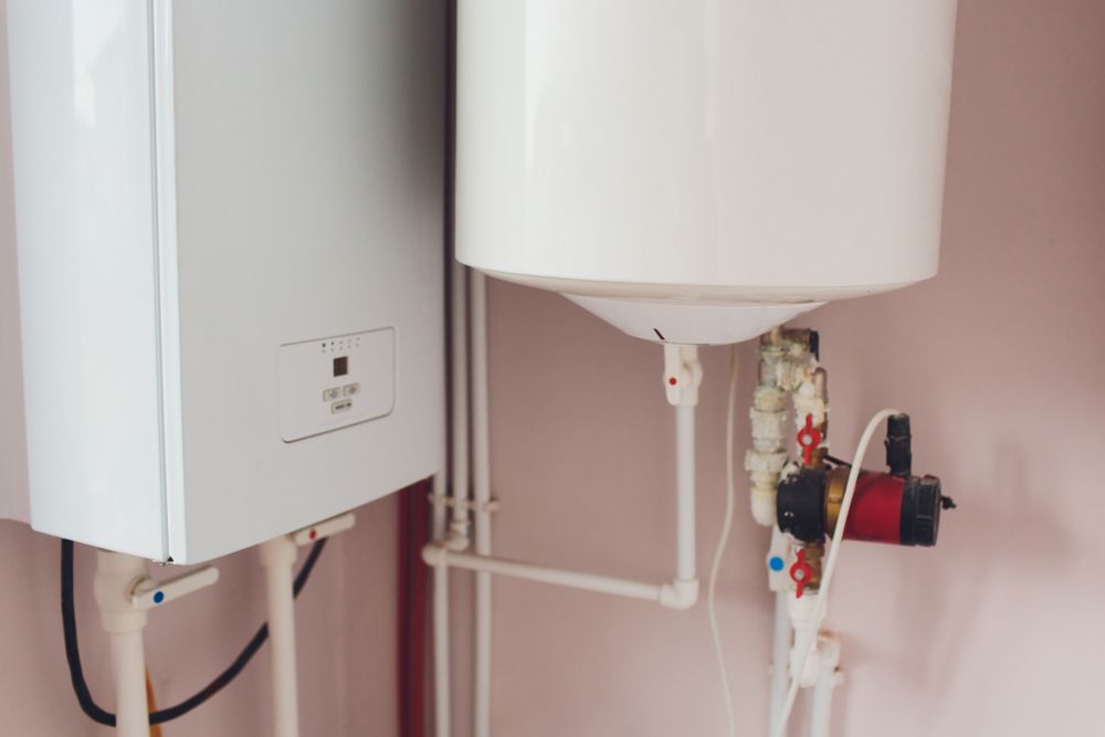 Two Water Heaters Are Sitting Next To Each Other In A Room — Tim Larkin Plumbing and Excavations in Bonny Hills, NSW