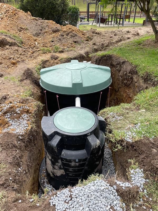 A Septic Tank With Three Green Lids And A White Pipe In The Grass — Tim Larkin Plumbing and Excavations in Laurieton, NSW