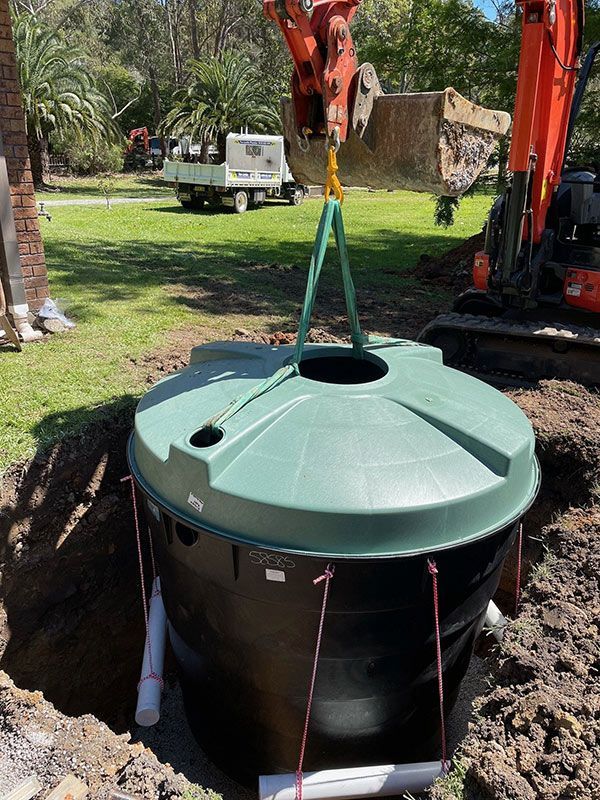 A Crane Is Lifting A Septic Tank Into The Ground For Installation — Tim Larkin Plumbing and Excavations in Wauchope, NSW