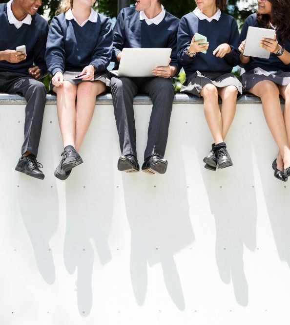 Group of students sat on a wall with their uniform on