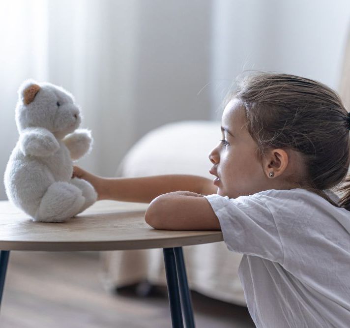 Child holding and looking at her teddy bear