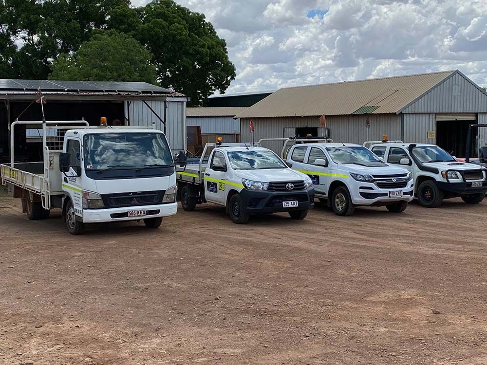 Row Of Trucks Parked In A Dirt Lot In Front Of A Building — Calibre Engineering In Mica Creak, QLD