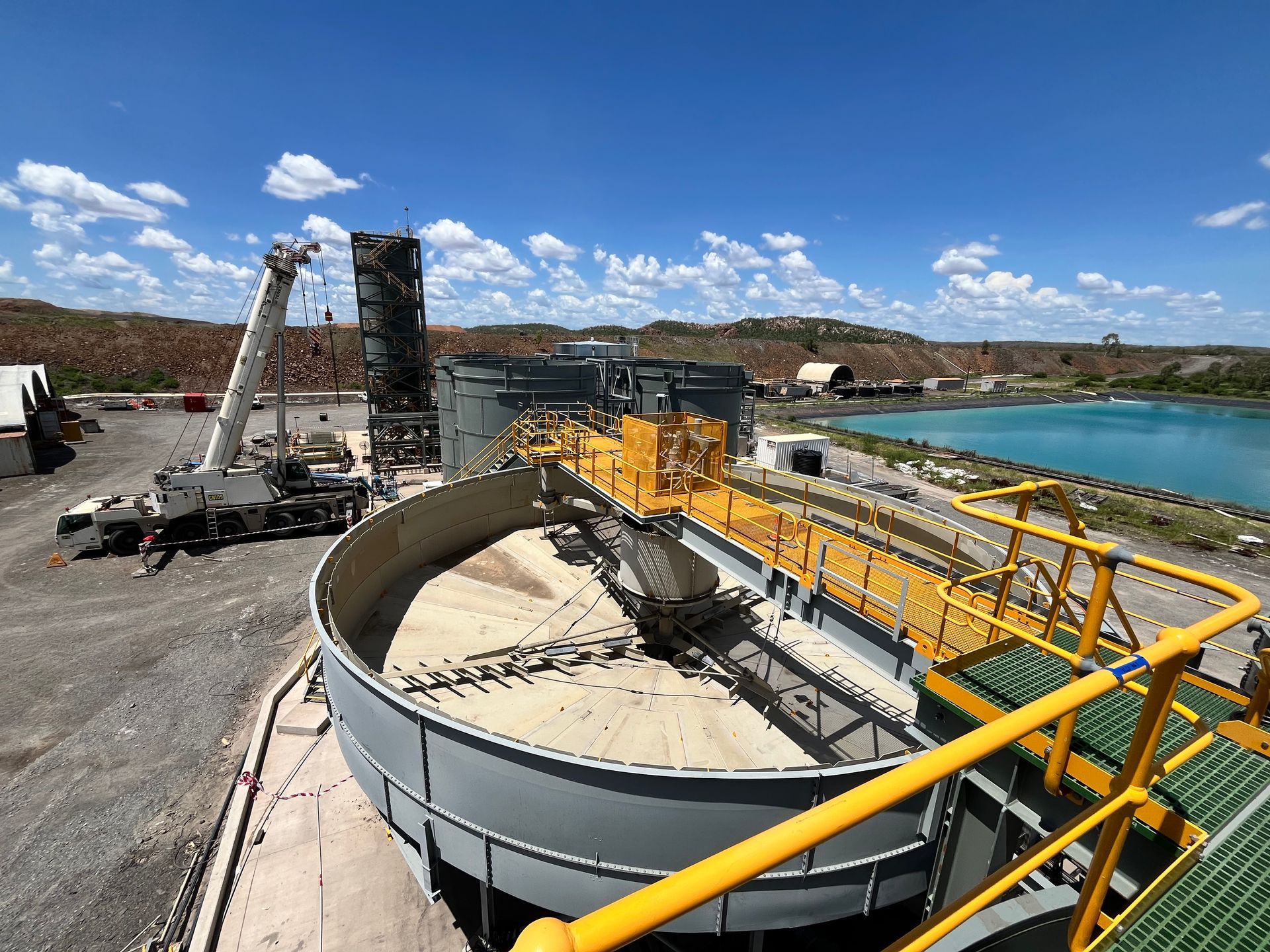 A large circular tank is sitting next to a large body of water — Calibre Engineering In Mica Creak, QLD