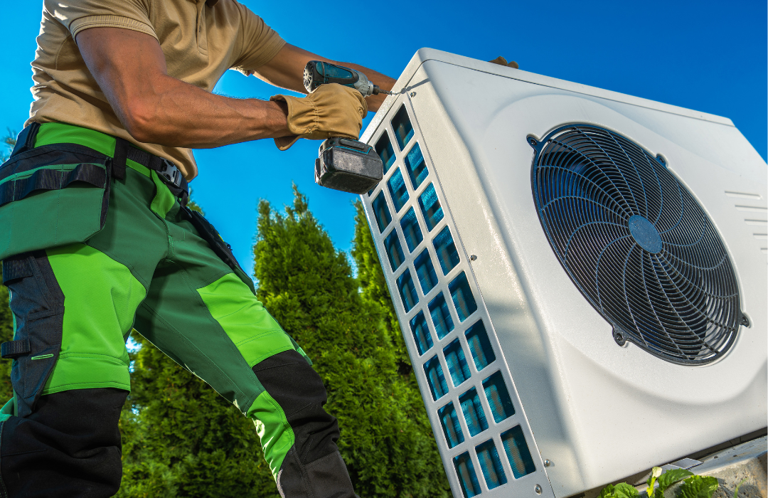 A man is fixing an air conditioner with a drill.