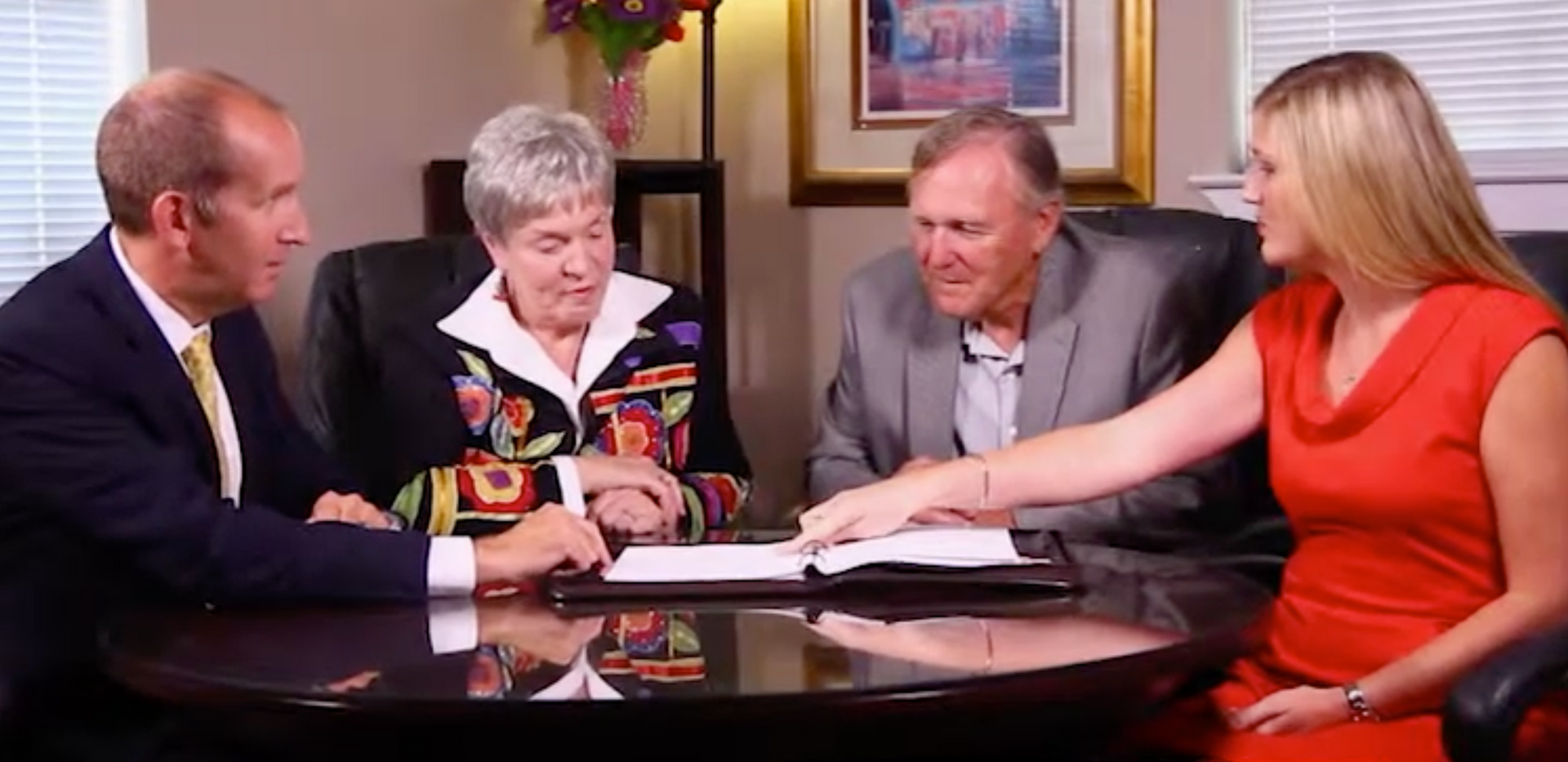 A group of people are sitting around a table talking to each other.