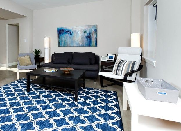 A living room with a blue rug and a black couch