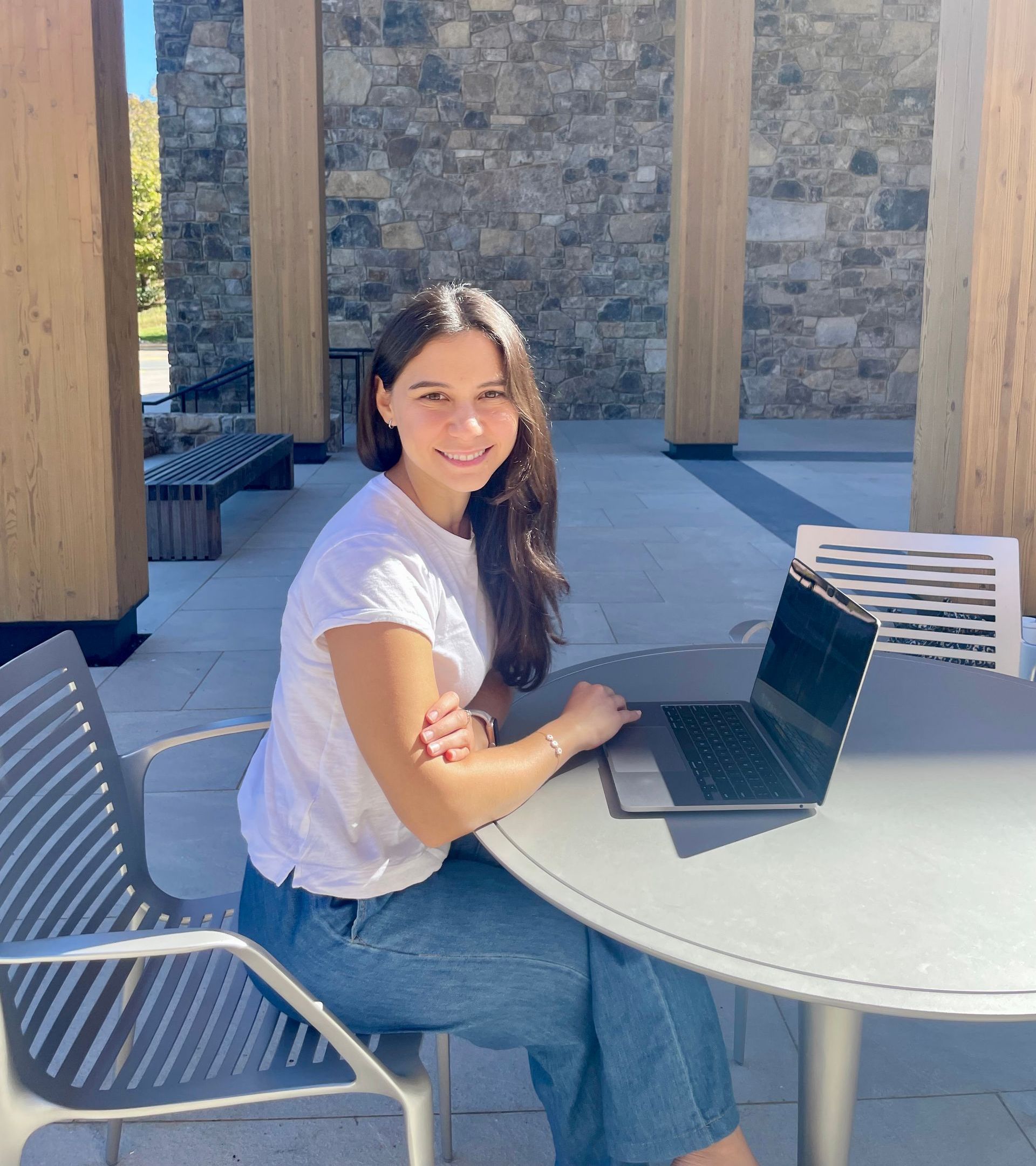 Daniela Canas Baena, a coach and team offsite consultant, sitting in front of a computer smiling.