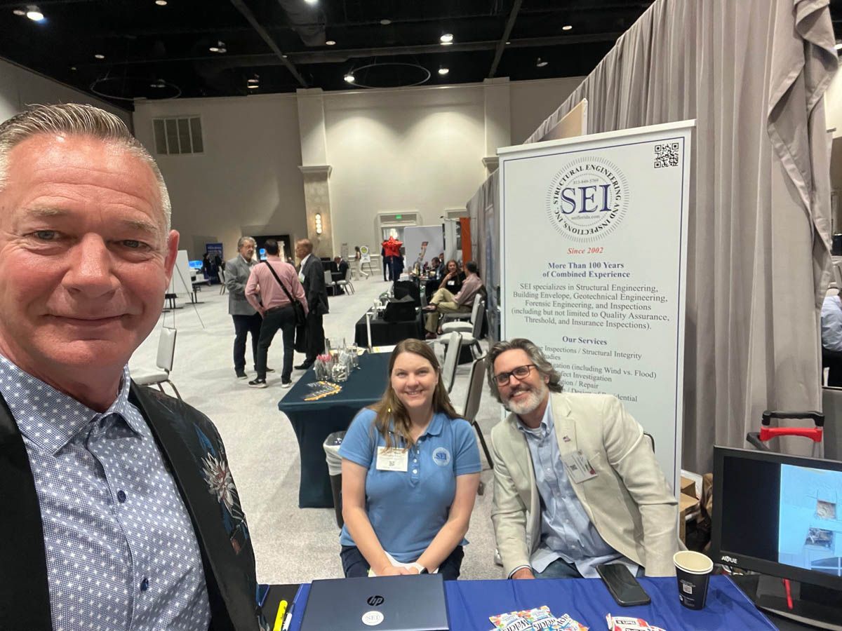 A man and two women are posing for a picture at a convention.