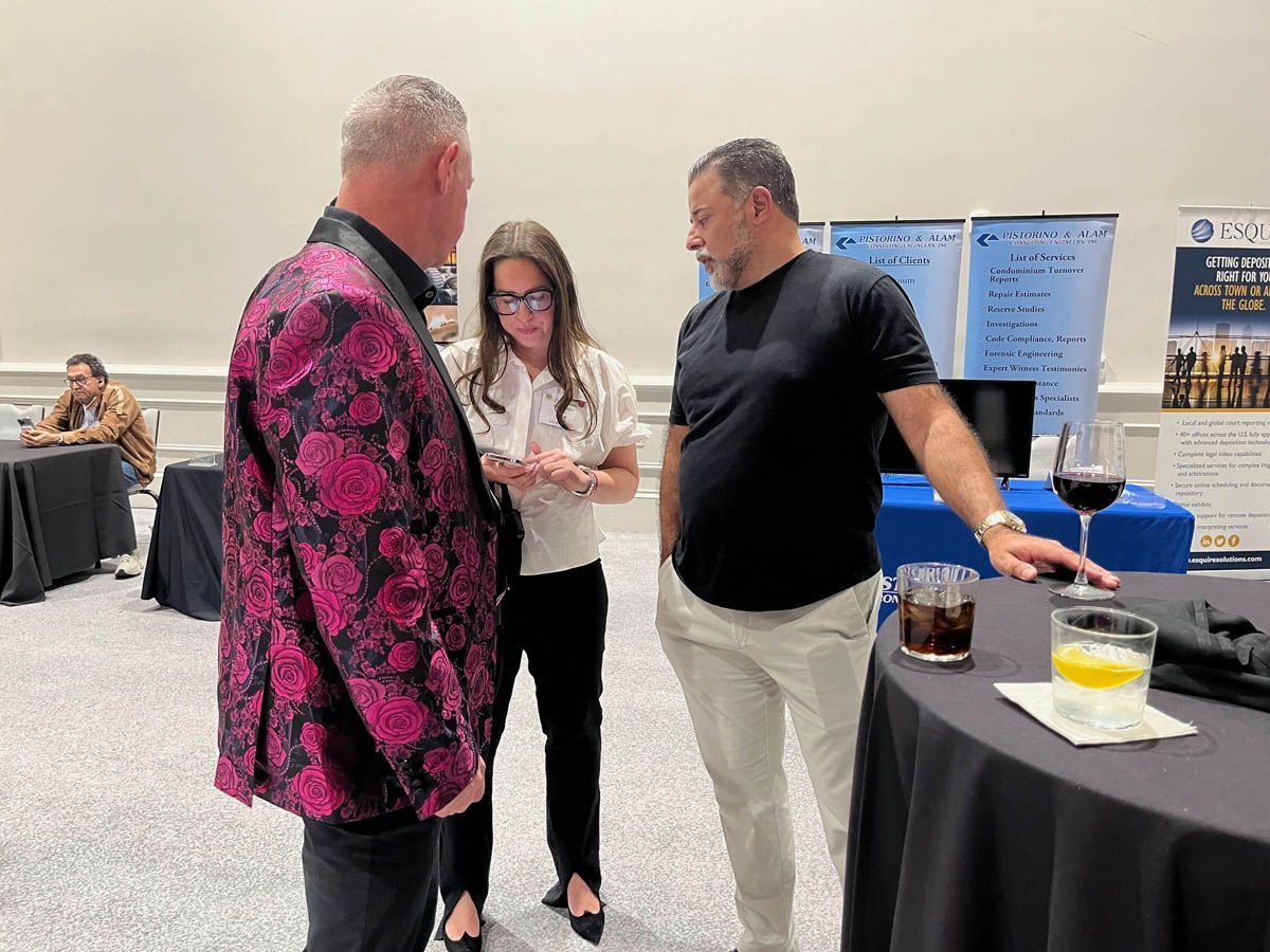 A group of people are standing around a table talking to each other.