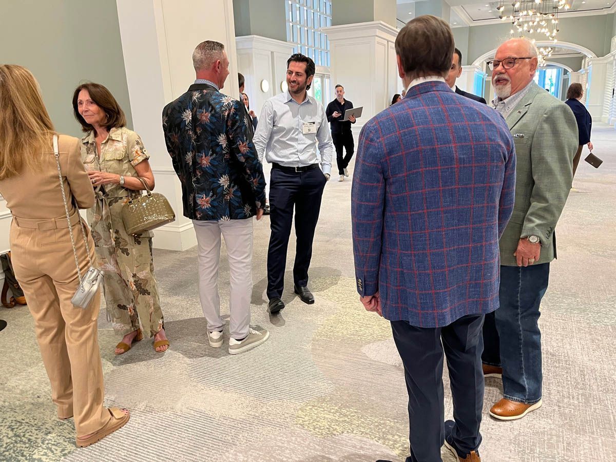 A group of people are standing in a room talking to each other.