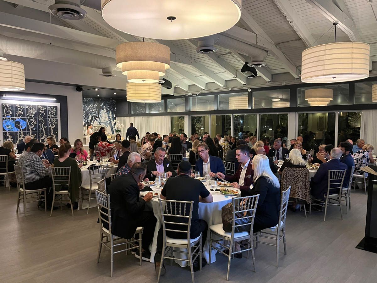 A large group of people are sitting at tables in a large room.
