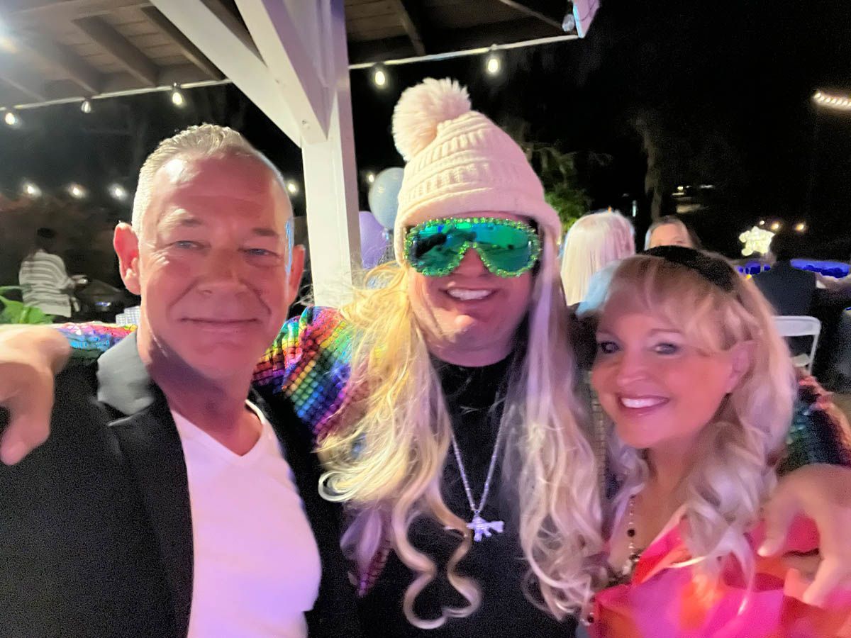 A man in a pink hat is posing for a picture with two other people