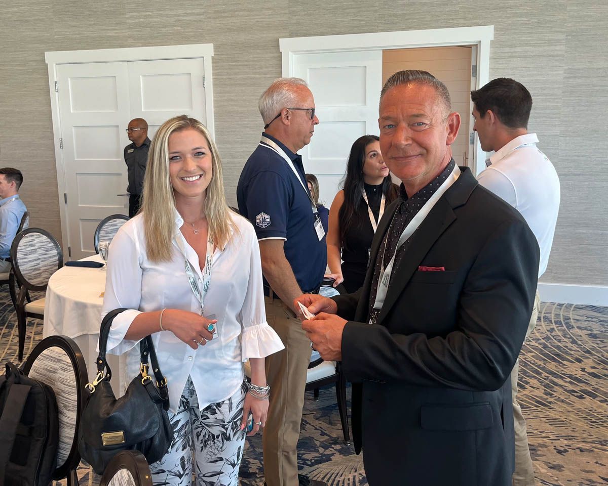 A group of people are standing in a room talking to each other.
