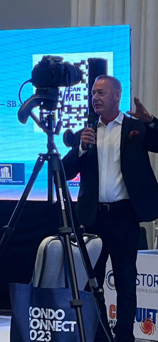 A man in a suit is standing in front of a camera and talking into a microphone.