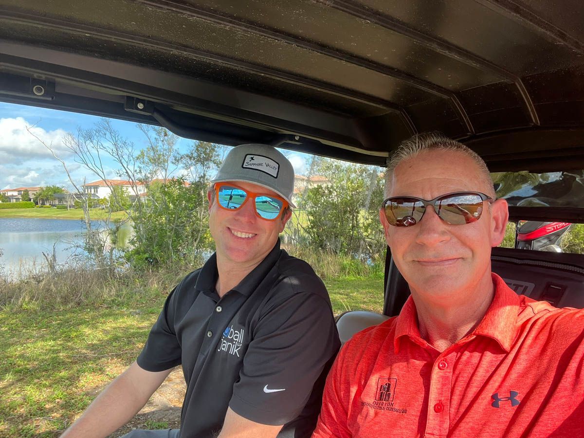 Two men are sitting in a golf cart next to each other.