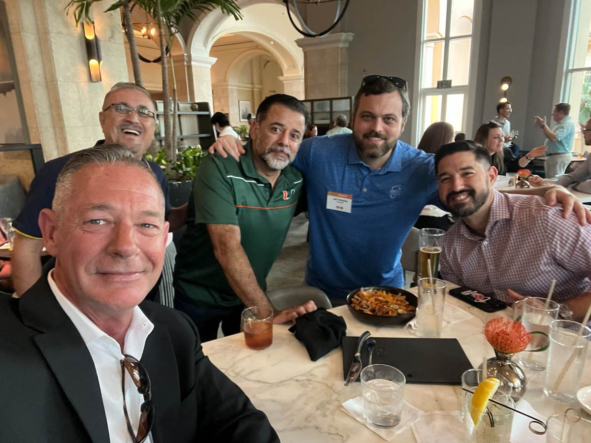 A group of men are posing for a picture at a table in a restaurant.