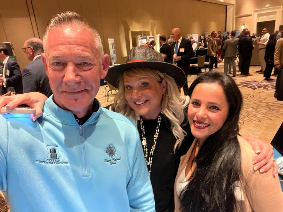 A man and two women are posing for a picture in a room.