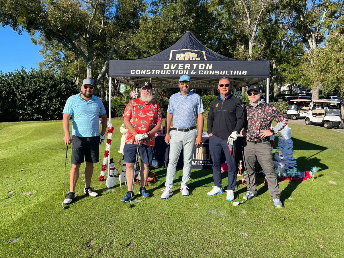 A group of men are standing under a tent on a golf course.