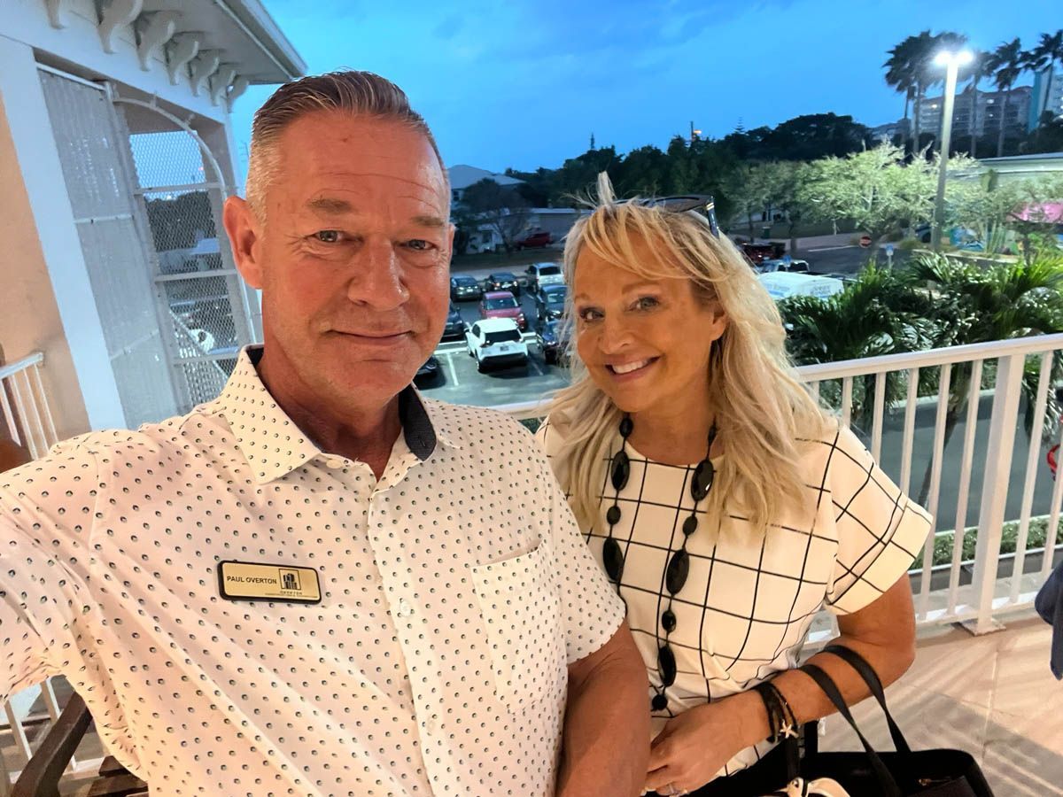 A man and a woman are posing for a picture on a balcony.