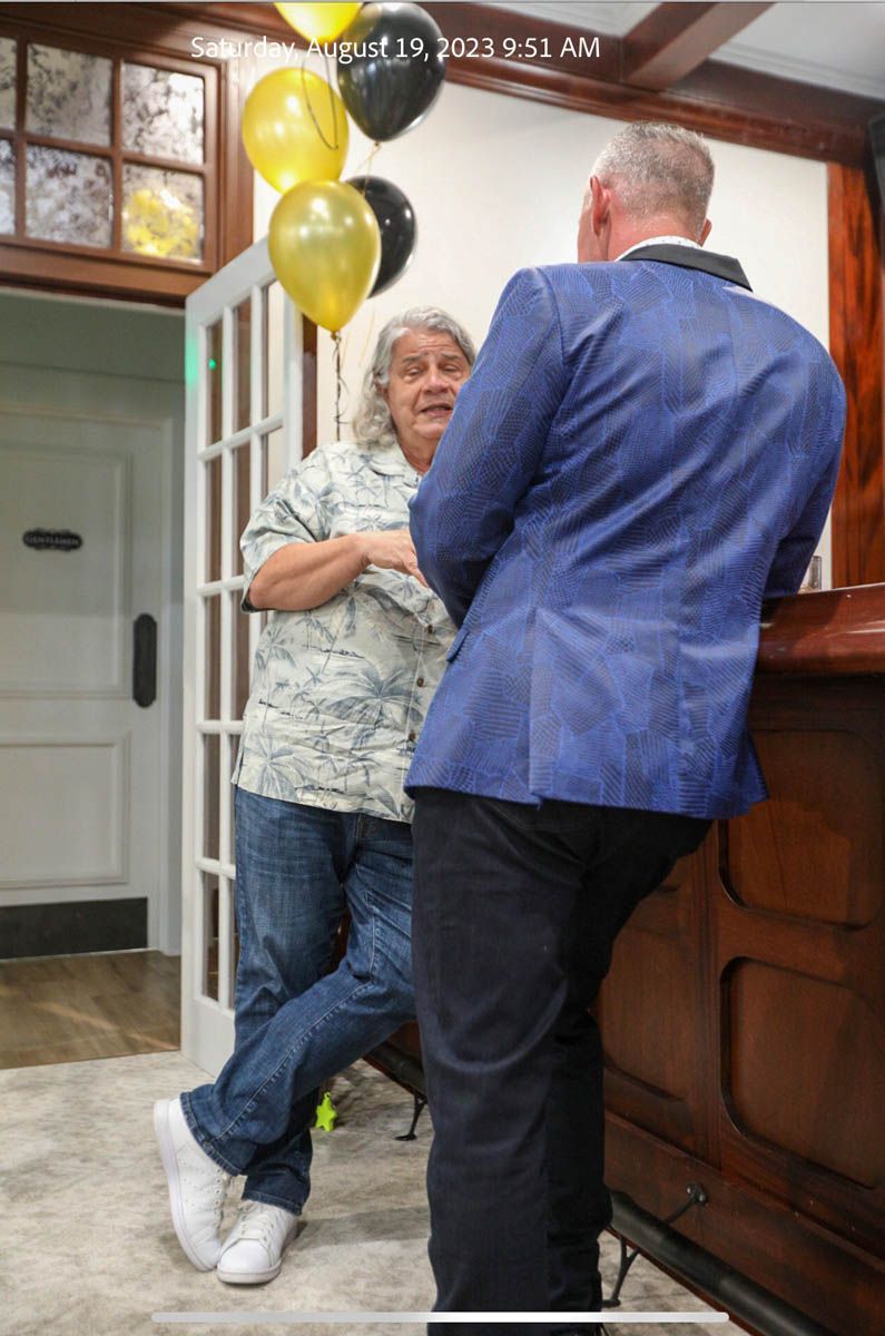 A man in a blue jacket is standing next to a woman in a white shirt.