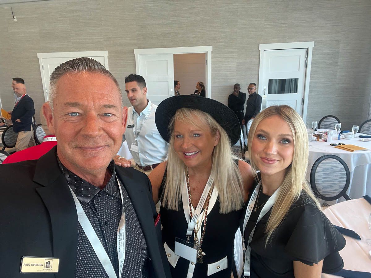 A man and two women are posing for a picture in a room.